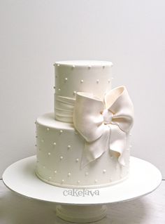 a three tiered white wedding cake with a large bow on the front and side