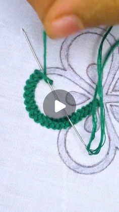 someone is stitching something on to a t - shirt with green thread and needles