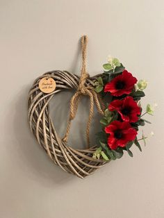 a heart shaped wreath with red flowers hanging on the wall