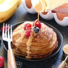 pancakes with syrup and berries on a black plate