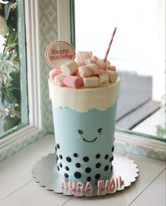 a birthday cake with marshmallows and candy on top in front of a window