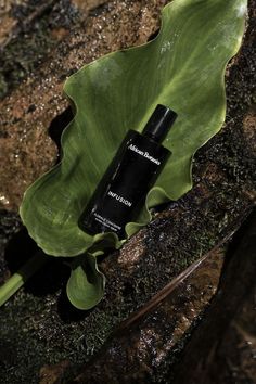 a black bottle sitting on top of a green leaf