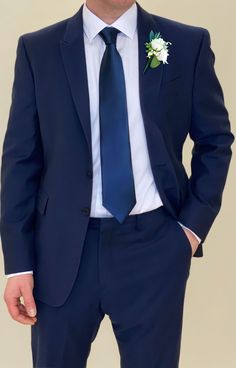 a man wearing a suit and tie with a boutonniere on his lapel