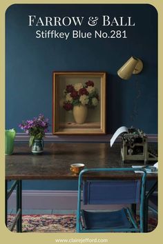 a blue room with an old fashioned typewriter on the desk and flowers in a vase