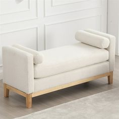 a white couch sitting on top of a hard wood floor next to a rug and wall