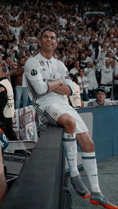 a man sitting on top of a bench in front of a group of people at a soccer game