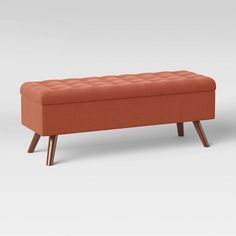 an orange bench sitting on top of a white floor next to a wooden frame and legs