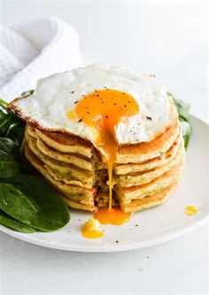 a stack of pancakes with an egg being drizzled over them on a plate