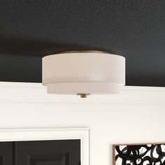 a white lamp hanging from the ceiling in a room with black door and framed pictures