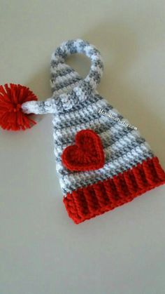 a crocheted hat with a heart on the front and a pom - pom attached to it