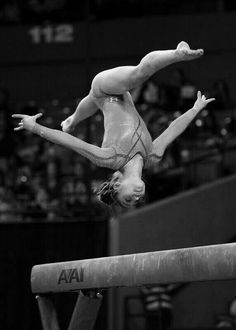 a woman is doing a handstand on the balance beam