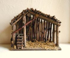 a nativity scene made out of sticks and logs, with a small house in the middle