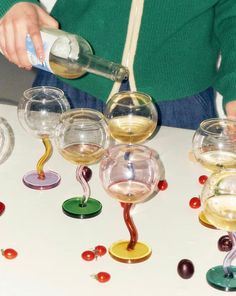 a person pouring wine into glasses on top of a table