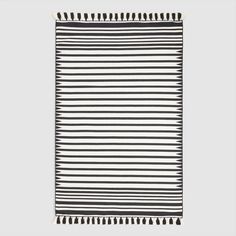 a black and white striped rug with tassels on the edges, in front of a gray background