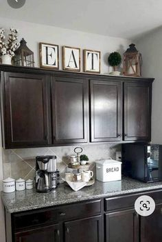 a kitchen with dark wood cabinets and white appliances on the counter top, along with pictures above it