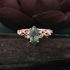 a close up view of a ring with an emerald stone in the center on a piece of wood