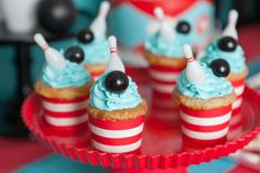 cupcakes with blue frosting and black eyes are on a red plate