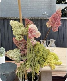 some flowers are sitting in a vase on a table outside with an umbrella over it