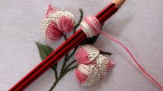 two crocheted flowers are next to a pencil