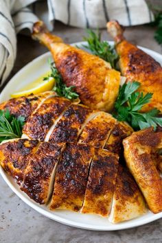 a white plate topped with sliced chicken and garnished with parsley