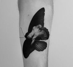 a black and white photo of a man's leg with a bird on it