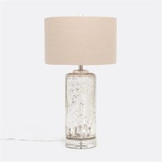 a glass table lamp with a beige shade on the base and a white fabric lampshade