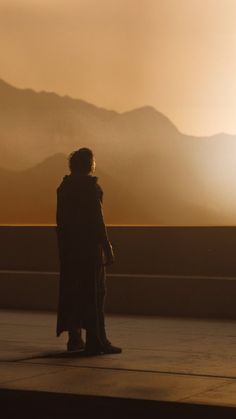 a person standing in front of mountains at sunset