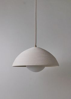 a white light hanging from a ceiling in a room with grey walls and flooring