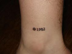 a person with a small tattoo on their ankle that reads 1932 and has the number two in it