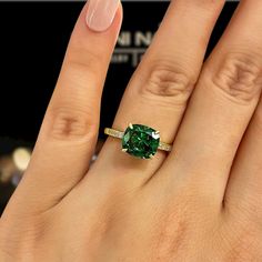 a woman's hand with a green ring on it