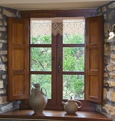 two vases are sitting on a window sill in front of a stone wall