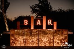 the bar is lit up at night with lights on it and letters that spell out