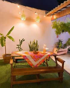 a table with candles on it sitting in the middle of a patio area surrounded by potted plants