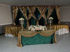 a banquet table with gold and green cloths, white flowers and candles on it