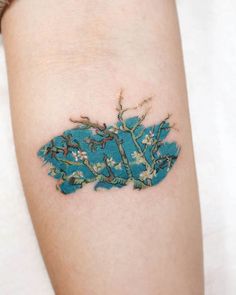 a woman's arm with a tattoo on it that has branches and flowers painted on it