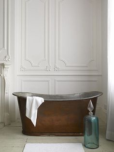 an old fashioned bathtub in the corner of a room with white walls and flooring