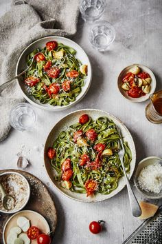 two plates of food on top of a table with utensils and wine glasses