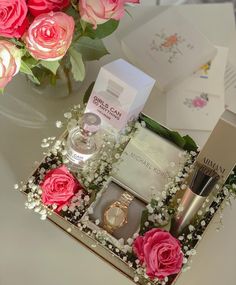 pink roses in a gift box with personal care items on a table next to it