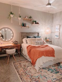 a bed room with a neatly made bed next to a desk and mirror on the wall