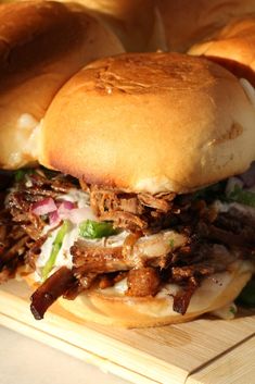 two pulled pork sandwiches sitting on top of a cutting board