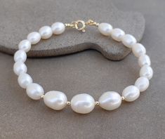 14k gold Oval pearl beaded bracelet Classic timeless bracelet made with fine materials Fresh water pearl with 14k solid gold clasp and spacer beads. High quality and luster of the pearls,you will get the bracelet you see in the picture. This bracelet fittes a 7 inch size and i can make it shorter.please see drop down menu for length Measures: pearls-8x10mm to 6x7mm 14k solid gold 6mm spring ring clasp Elegant Hand-strung Bracelets With Oval Beads, Elegant Gold Bracelets With Oval Beads, Elegant Oval Bead Pearl Jewelry, Elegant Pearl Jewelry With Oval Beads, Unique Bridal Earrings, Leather Silver Bracelet, Modern Pearl Jewelry, Timeless Bracelet, Pink Pearl Bracelet