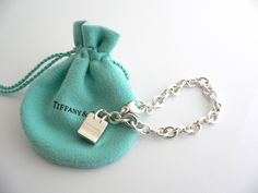 Overview: Here is a gift that she will surely adore! It is shiny, stylish, and super versatile! This piece will make someone REALLY happy! :) Offered for sale is a wonderful Tiffany & Co. Sterling Silver Signature Shopping Bag Charm Bracelet. Hanging from its bright Tiffany silver chain is a very pretty Shopping Bag charm with the words "Tiffany & Co" on it! A classic Tiffany piece that any girl will adore! Very pretty and just an adorable piece! It is simple, elegant, and classic all rolled int Luxury Bracelets With Logo Charm As Gift, Elegant Bracelets With Logo Charm For Gift, Designer Rectangular Bracelets As Gift, Elegant Bracelets With Logo Charm As Gift, Luxury Rectangular Bracelet Gift, Luxury Rectangular Bracelet As Gift, Palladium Hardware Bracelets As Gift, Luxury Bags With Logo Charm For Gift, Tiffany Gifts