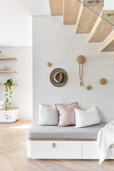 a white couch sitting under a wooden ceiling next to a shelf filled with pillows and hats