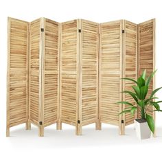 a wooden room divider next to a potted plant