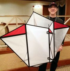 a man standing in front of a bed holding a white and red kite with black sides