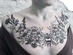 a woman wearing a black and white tattoo on her chest with flowers in the middle