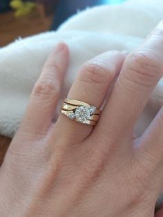 a woman's hand with a gold ring and two diamond rings on her fingers