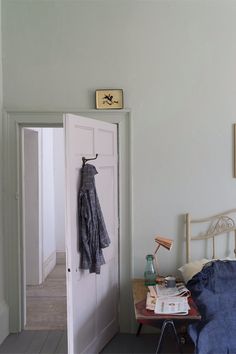 an open door leading to a bedroom with clothes hanging on the hooks and a bed