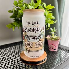 a can with the words, the lord is strength on it sitting on a table next to a potted plant