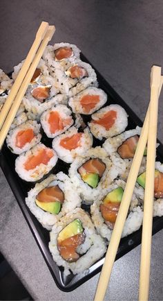 sushi and chopsticks on a black tray